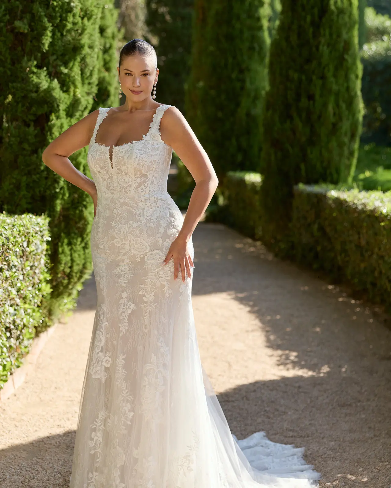 Abito da sposa con spalline decorate, motivi floreali, linea aderente e gonna che si apre verso il fondo.