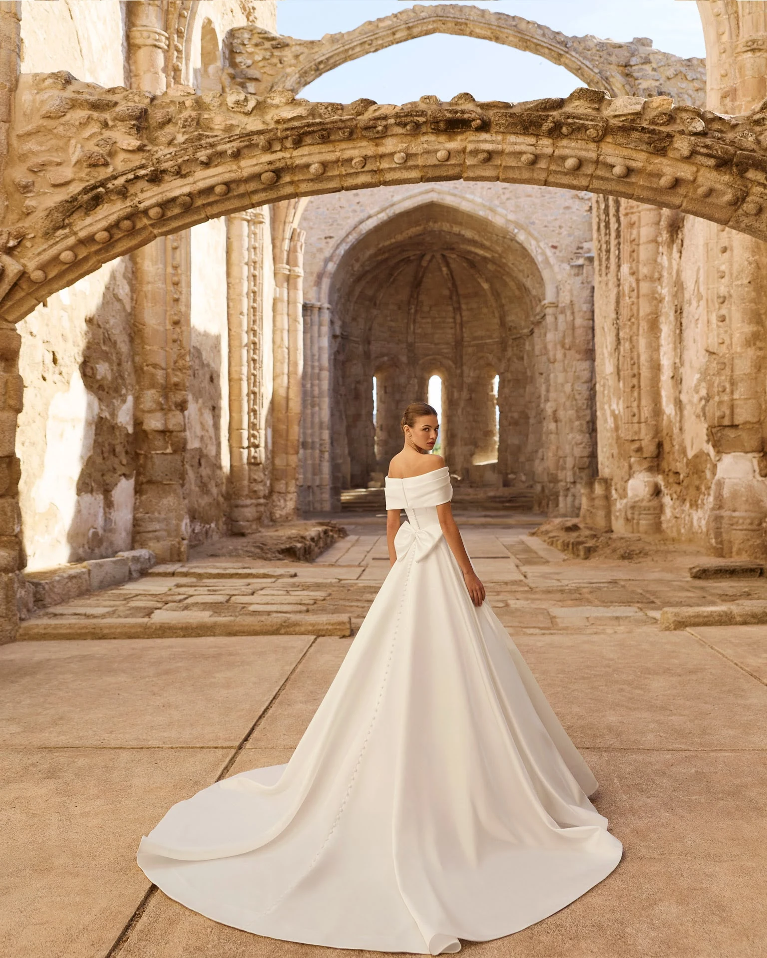 Abito da sposa AIRE Atelier: strascico disteso tra le architetture in pietra