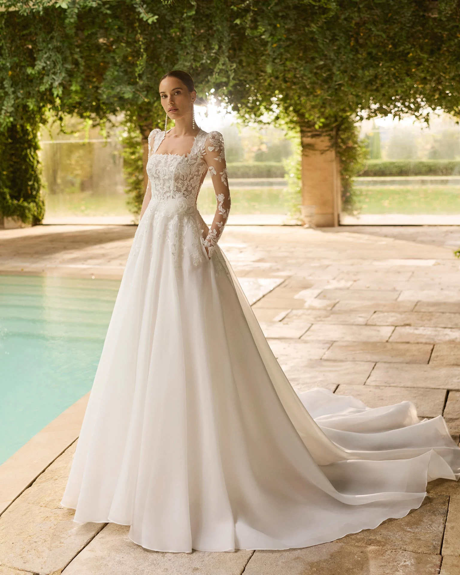 Abito da sposa AIRE: maniche lunghe e gonna ampia accanto alla piscina