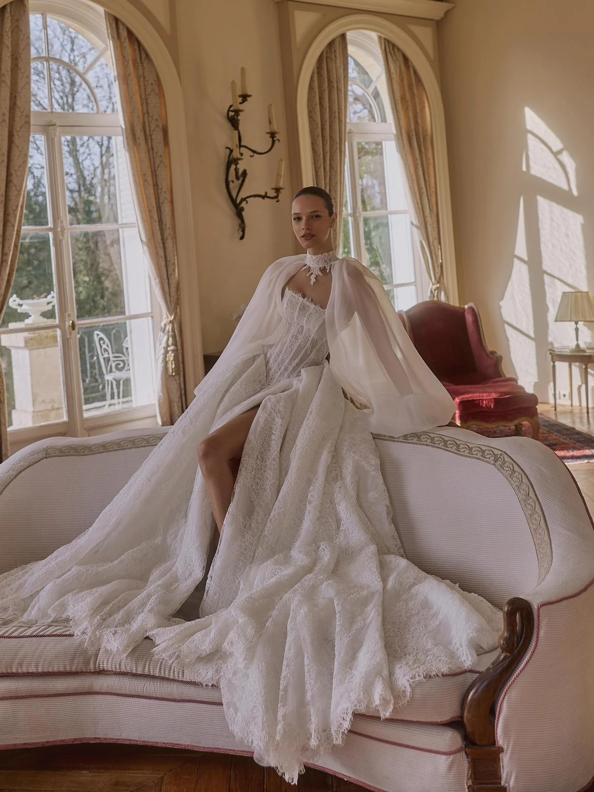 Abito da sposa con maniche ampie e gonna distesa su un divano. — selezione Maison Yana, riferimento 029