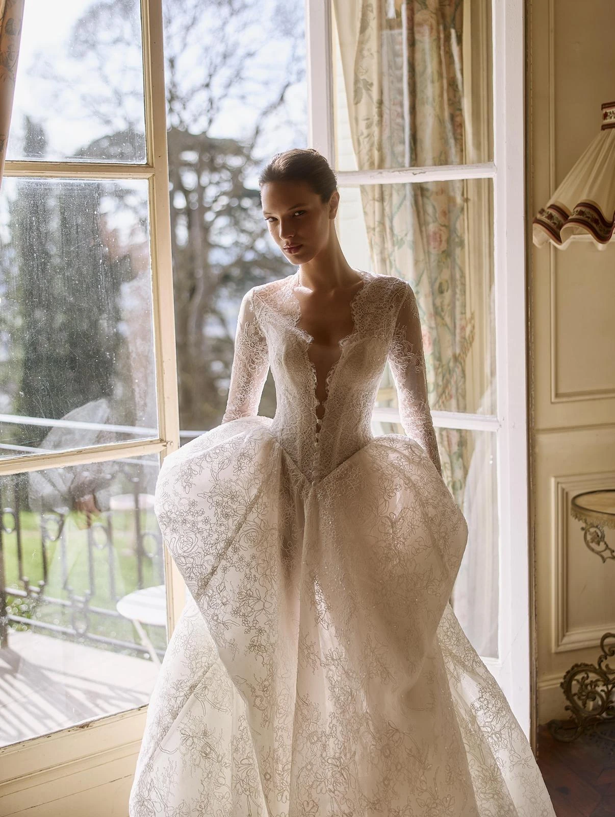 Abito da sposa con corpetto strutturato e gonna ampia accanto alla finestra. — selezione Maison Yana, riferimento 026