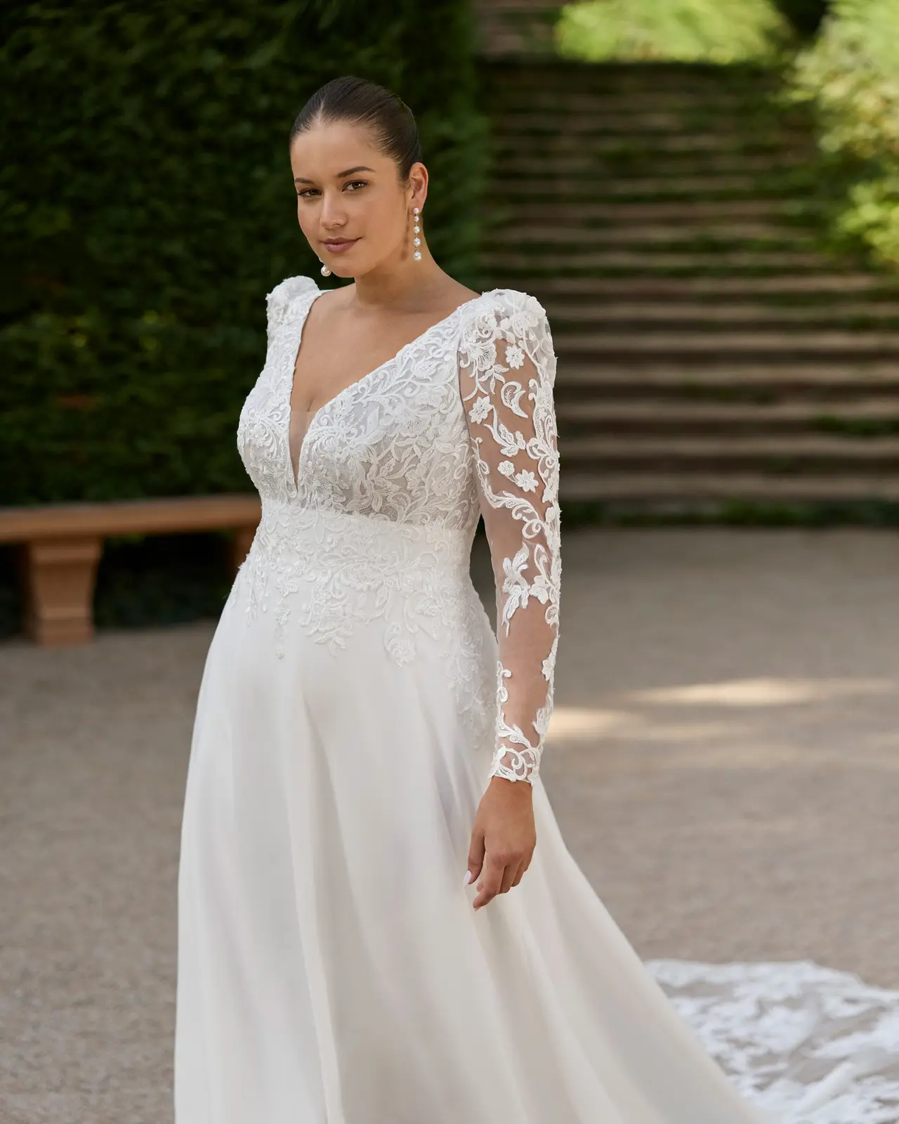 Abito da sposa con scollatura a V, corpetto decorato, maniche lunghe trasparenti e gonna liscia.
