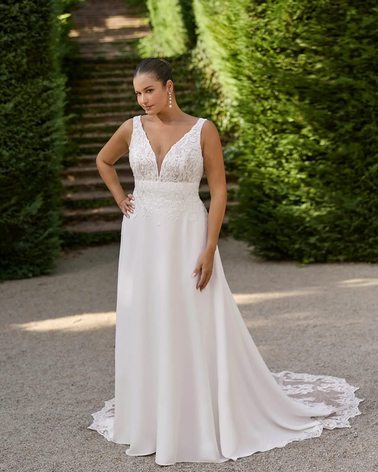 Abito da sposa senza maniche, con scollatura a V, corpetto floreale, fascia decorata in vita e gonna liscia con strascico.