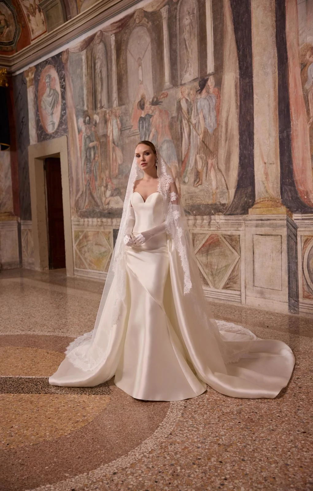 Abito da sposa Madeline Gardner: abito con velo nella sala affrescata