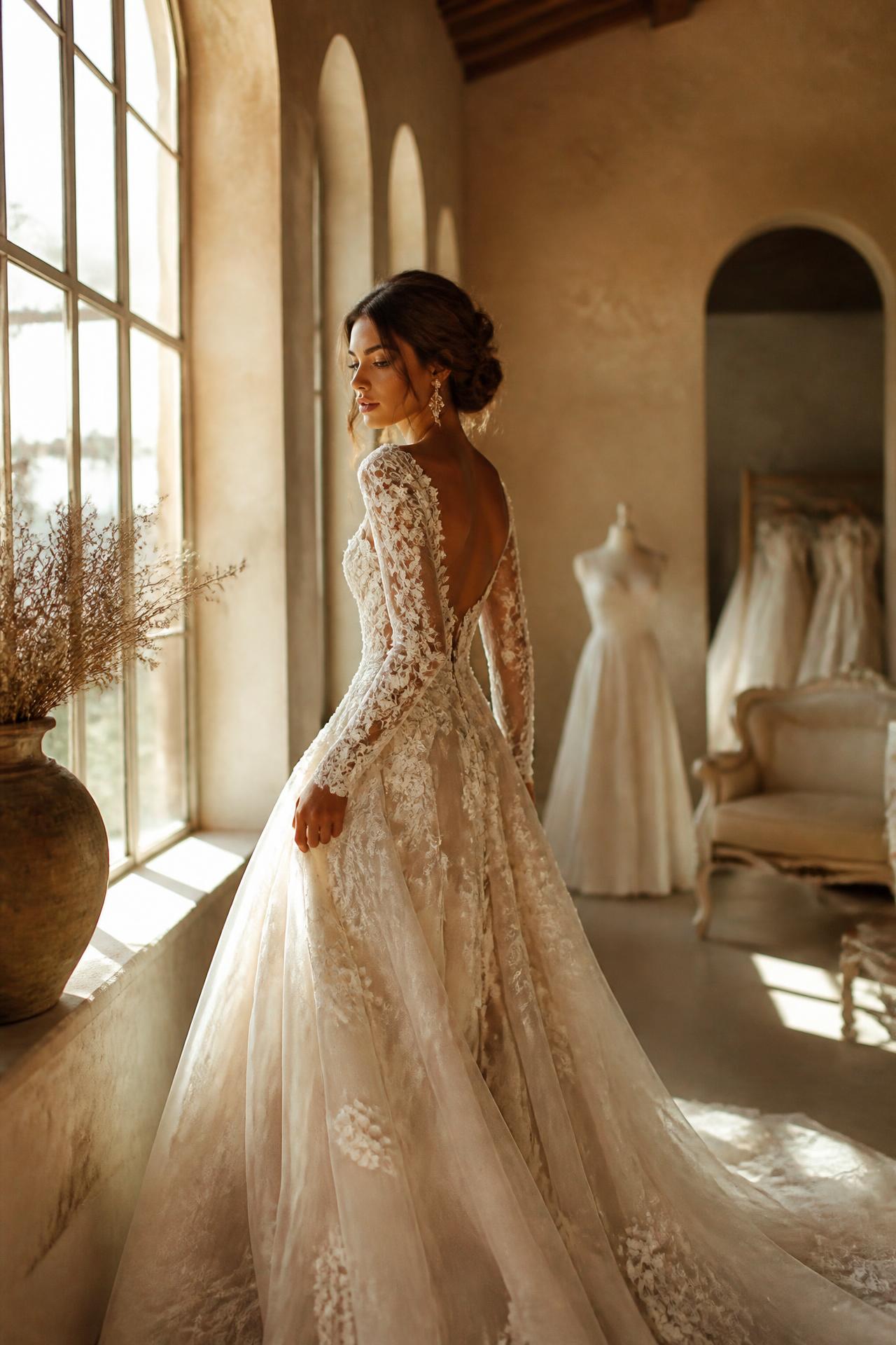 Sposa con abito in pizzo nella luce di un atelier toscano